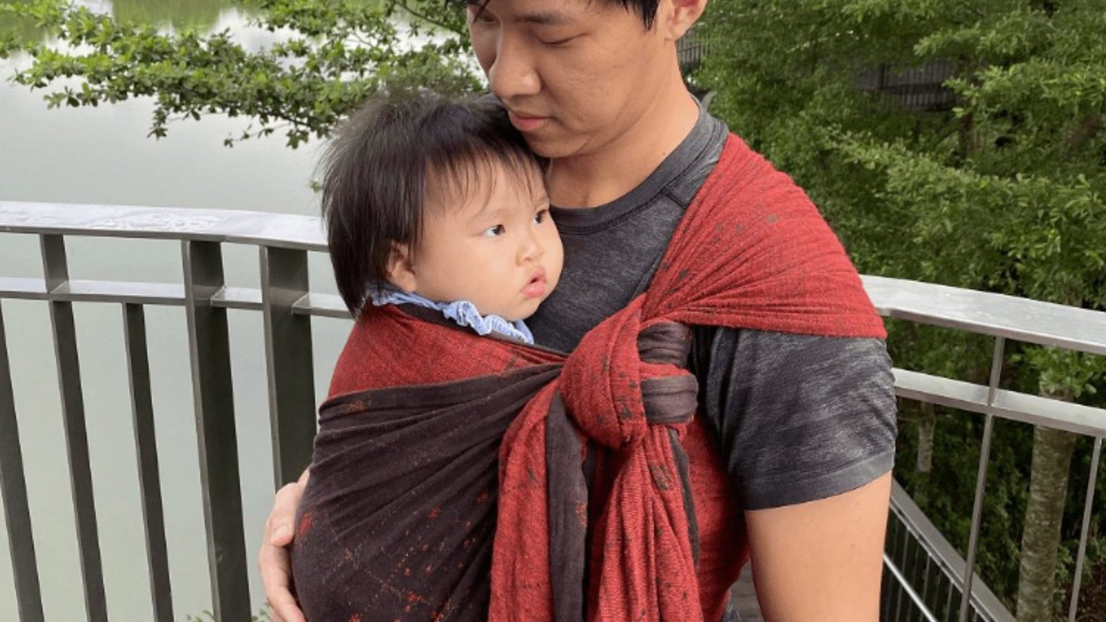 An Asian Carrying a Baby with a Sling 