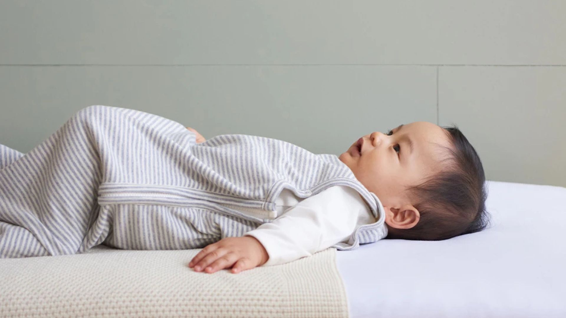 A baby Sleeping on the Bed in a Sleeping Bag